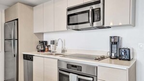 Eine moderne Küche mit Edelstahlgeräten, darunter eine Mikrowelle, eine Kaffeemaschine und ein Geschirrspüler.