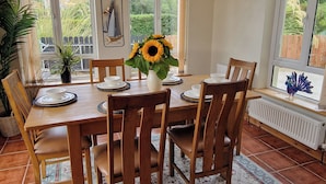 Un'area pranzo con un tavolo in legno, sedie e un vaso di girasoli.