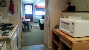 A kitchen with a microwave, a sink, and a dining area with a table and chairs.