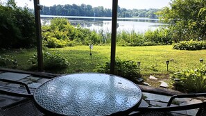 Une table en verre offrant une vue sur un lac et la végétation environnante.