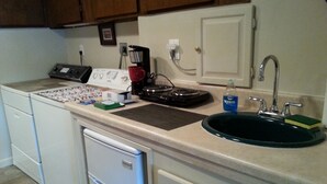 A kitchen with a dishwasher, a coffee maker, a sink, and a countertop with various items.