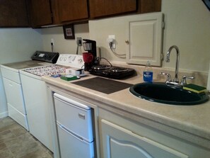 A kitchen with a dishwasher, a coffee maker, a sink, and a countertop with various items.