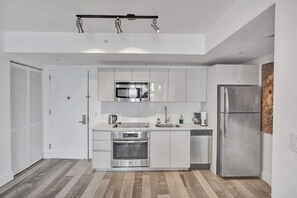 Une cuisine moderne avec des armoires blanches, des appareils en acier inoxydable et un plancher en bois.