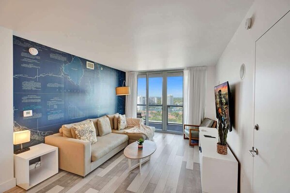 Un salon moderne avec une grande carte murale, un canapé, une table basse et une vue sur la ville grâce à de grandes fenêtres.