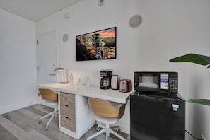 Cocina compacta con microondas, tostadora y cafetera sobre una encimera blanca.