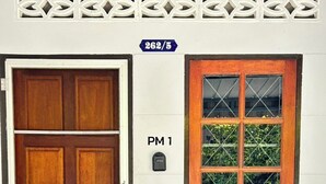 A double wooden door with a white frame, a window with a wooden frame and glass panes, and a number plate "262/5" above the door. - The Endless Bangtao Residence: PM1 (Thalang)