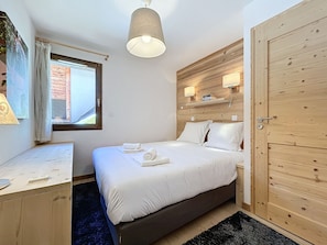 Quarto com cama, escrivaninha, janela e porta.