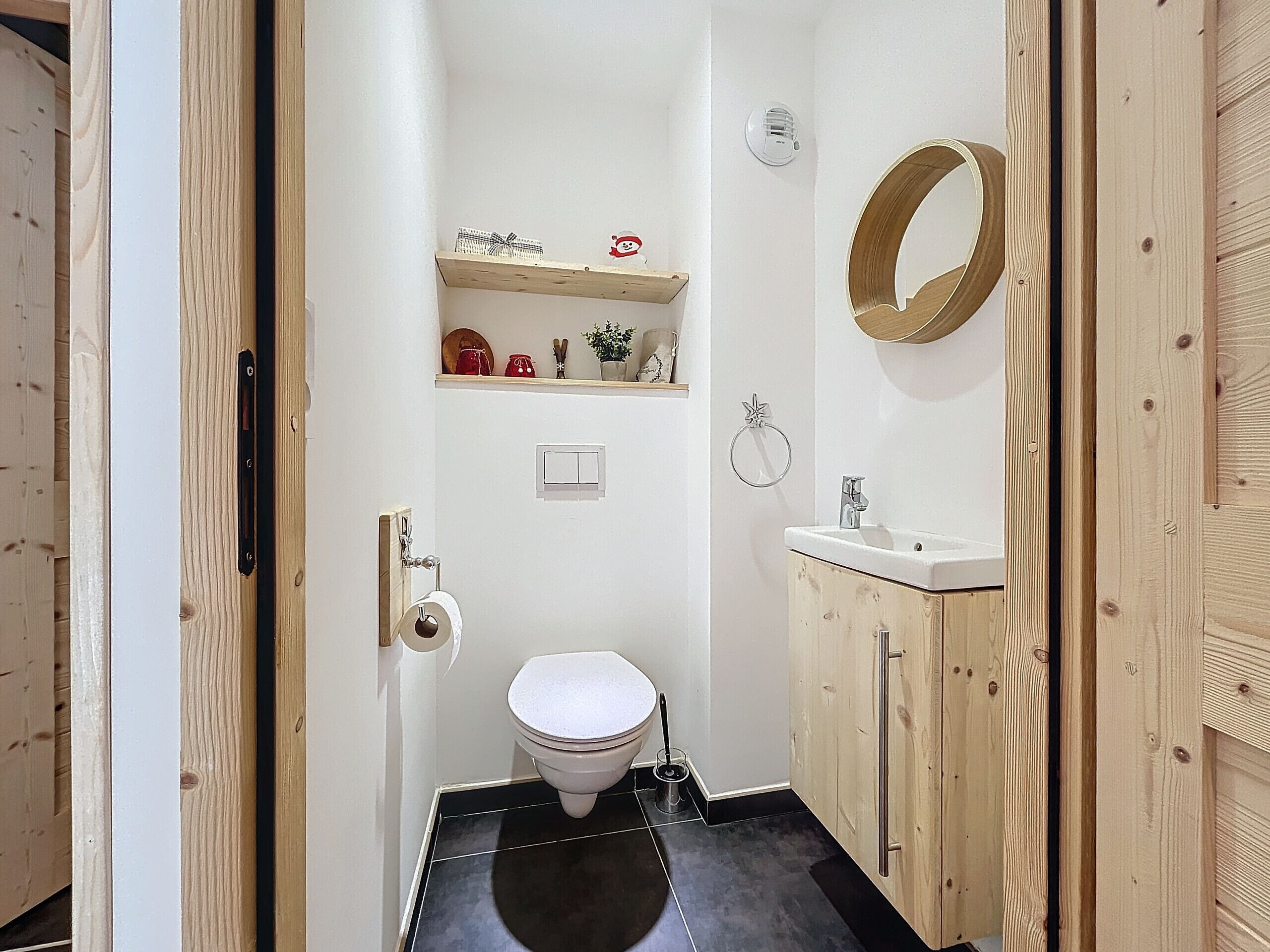 A compact bathroom with a toilet, sink, and wooden cabinets.