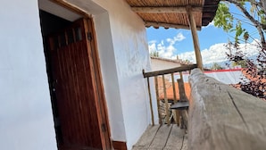 A wooden balcony with a bamboo roof, a wooden door, and a welcome mat. - SUMAQ QUINUA (Carmen Alto)