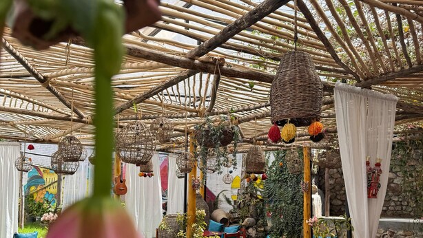 An indoor garden with a thatched roof, wooden furniture, and hanging planters. - SUMAQ QUINUA (Carmen Alto)