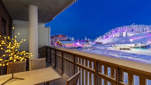 A balcony with a view of a snow-covered ski resort at night. - Ruka chalets 2 huoneisto 2405 by Interhome (Kuusamo)