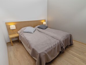 A single bed with a wooden headboard, two bedside tables, and a nightstand with a lamp.