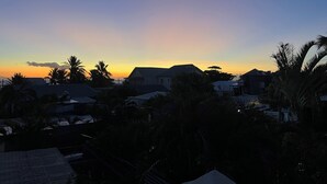 Een woonwijk met huizen en palmbomen in de zonsondergang.