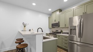 A modern kitchen with a central island, stainless steel appliances, and green cabinetry. - Juneau Family Friendly Getaway 301 (Juneau)