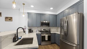 A modern kitchen with grey cabinets, stainless steel appliances, a marble countertop, and a wooden floor. - Accessible, Comfort, Convenient Location 106 (Juneau)
