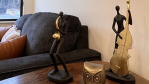 A room with a sofa, a table with sculptures, and a framed picture on the wall. - Accessible, Comfort, Convenient Location 106 (Juneau)