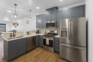A modern kitchen with grey cabinets, stainless steel appliances, and a wooden floor. - Cozy Retreat With Breath Taking Views 303 (Juneau)