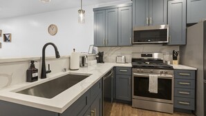 Una cocina moderna con armarios grises, electrodomésticos de acero inoxidable, un lavamanos doble y piso de madera.