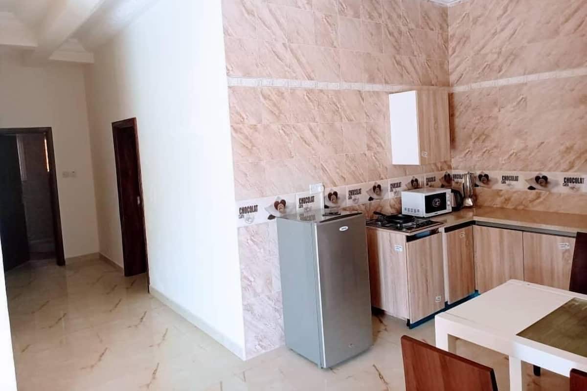 A kitchen with marble walls, a refrigerator, a microwave, and a dining table.