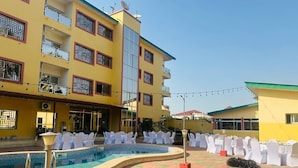 Un patio de hotel con piscina, mobiliario exterior y un edificio con balcones.