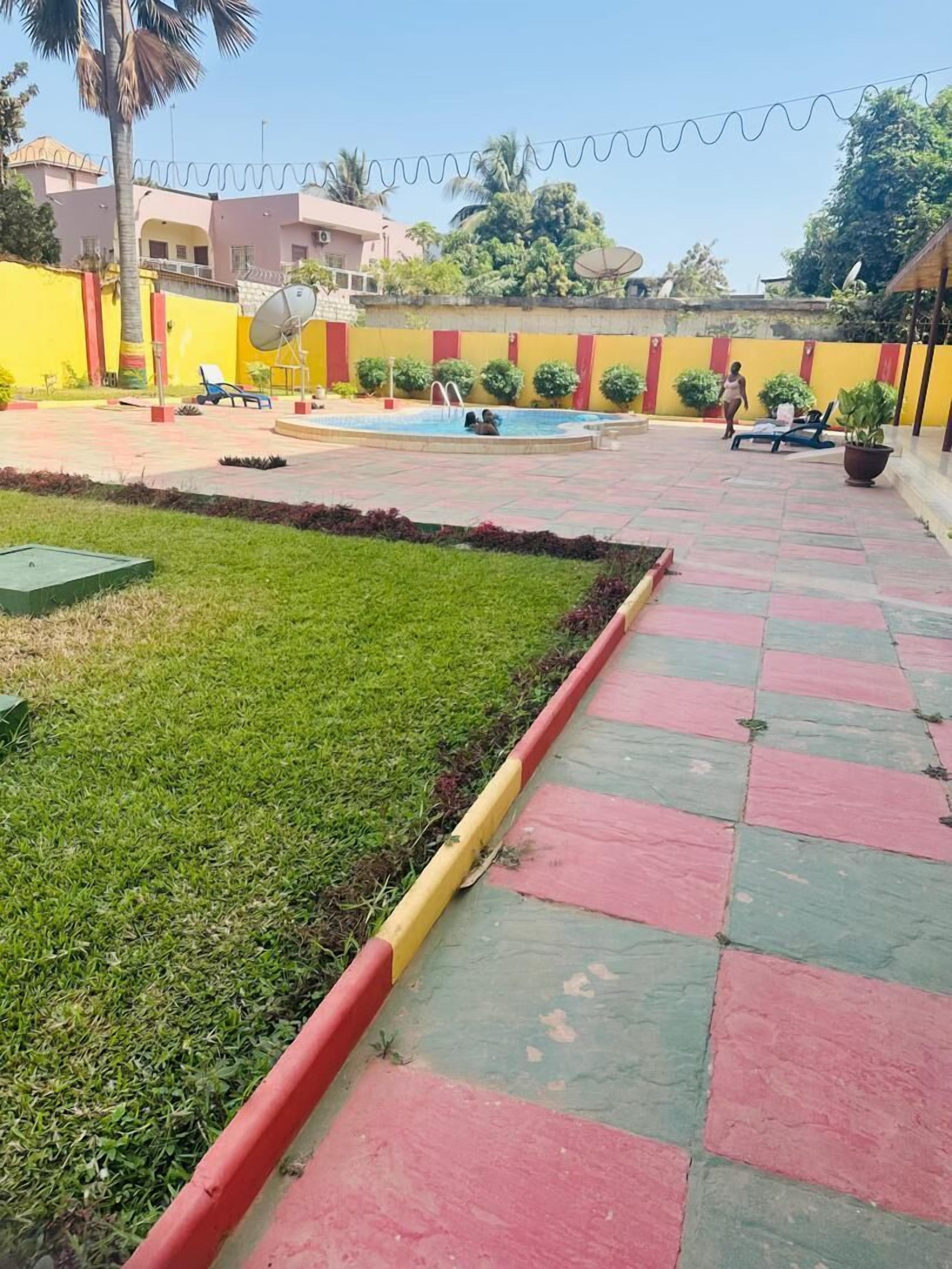 A courtyard with a swimming pool, a grassy area, and a tiled walkway.