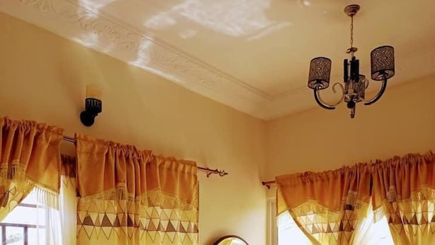 Habitación de hotel con cama, escritorio, silla y una ventana grande con cortinas.