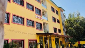 Un edificio amarillo con marcos de ventanas rojos y un letrero que dice "Akka2 Suites".