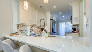 Una cocina moderna con encimera de mármol, electrodomésticos de acero inoxidable y asientos de bar.