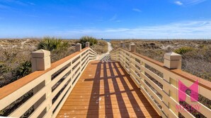 Un paseo marítimo de madera que conduce a una playa con cielo despejado.