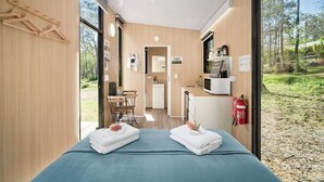 A modern room with a bed, a small kitchenette, and a view of the outdoors.