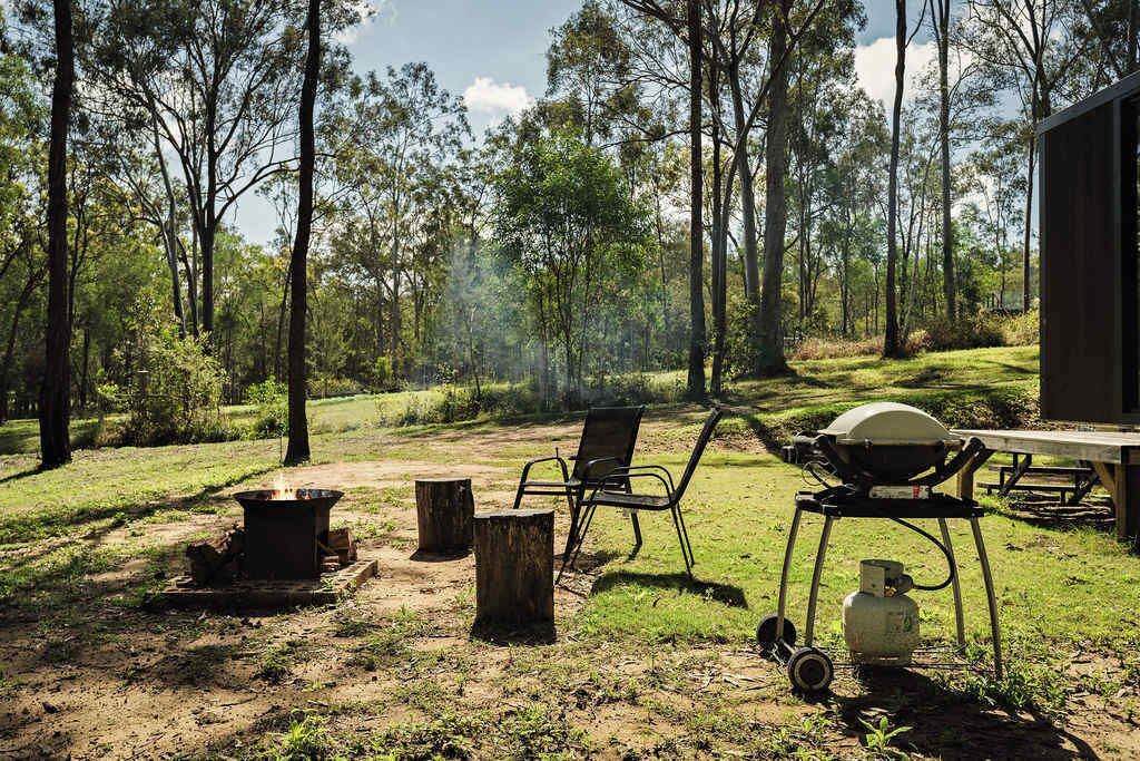 An outdoor camping area with a grill, chairs, and a table.