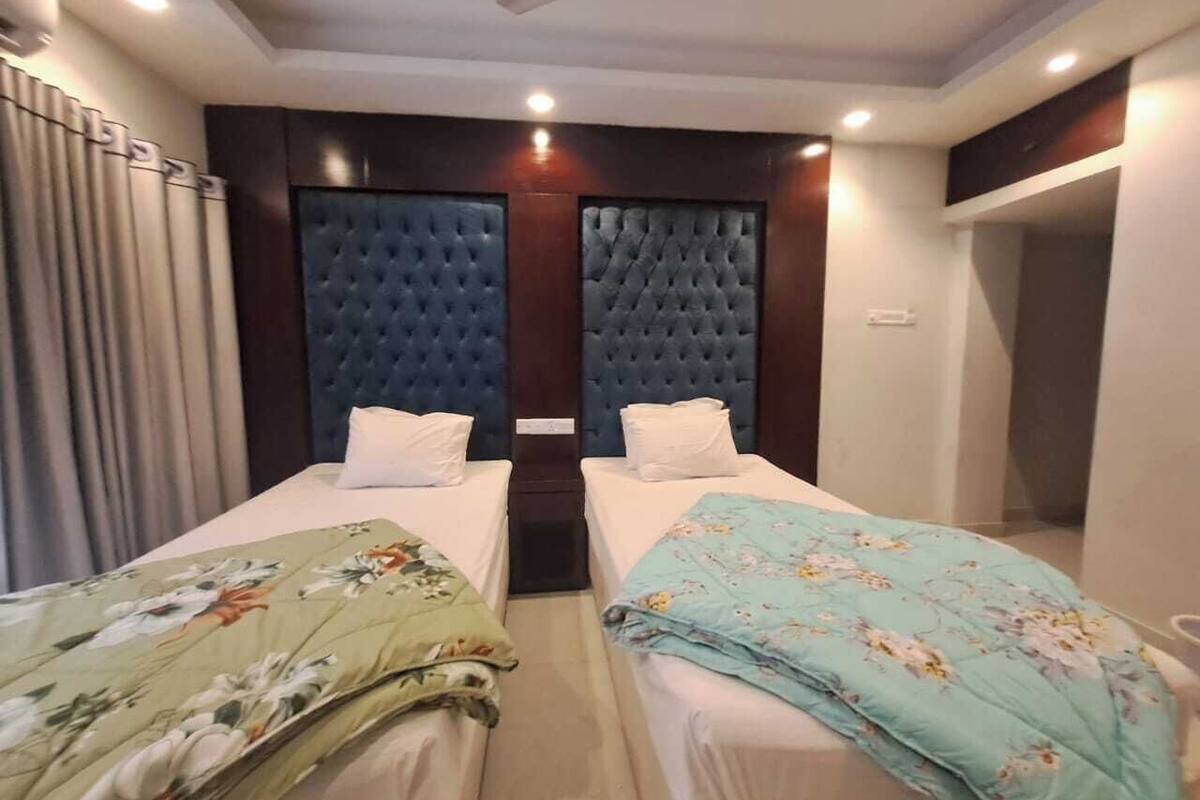 Ein Hotelzimmer mit zwei Einzelbetten, einem Deckenventilator und einem kleinen Fenster.