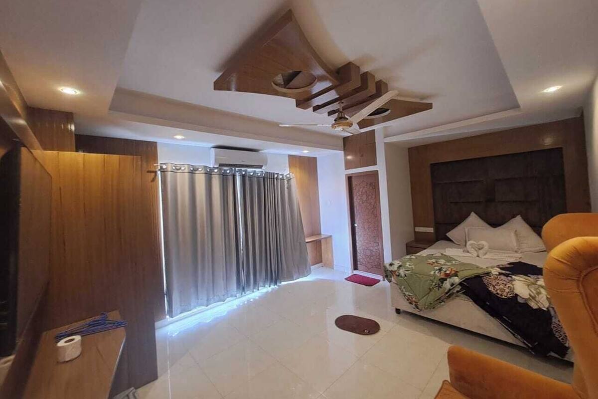 Ein modernes Hotelzimmer mit einem großen Bett, einem Fernseher und einem Holzschrank.