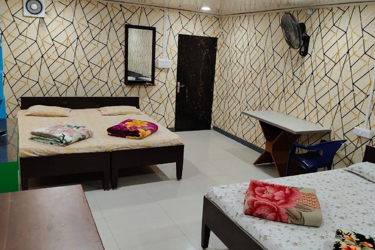 A bedroom with two beds, a desk, and a chair.