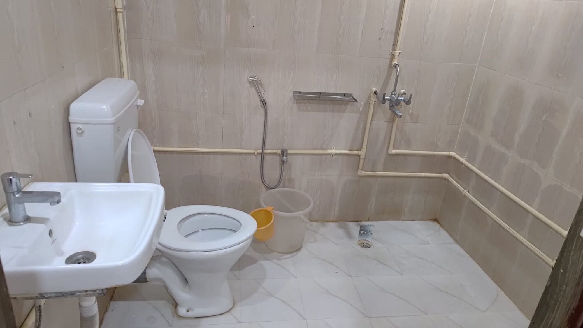 A small bathroom with a toilet, sink, and shower.