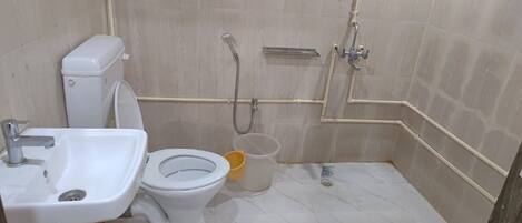 A small bathroom with a toilet, sink, and shower.
