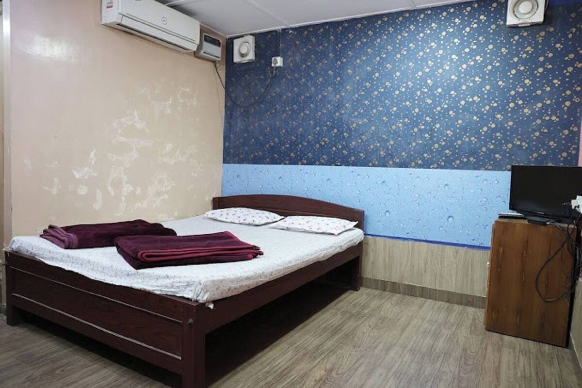 A bedroom with a bed, a TV, and a wooden cabinet.