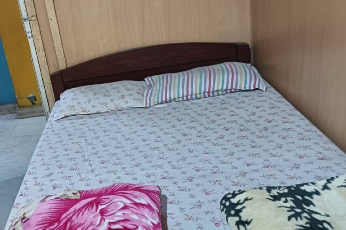 A bedroom with a bed, floral patterned bedspread, a striped pillow, and a floral pillow.