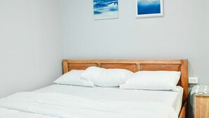 A neatly made bed with white bedding in a room with light-colored walls. - DOS MARIAS TOURIST INN (Daanbantayan)