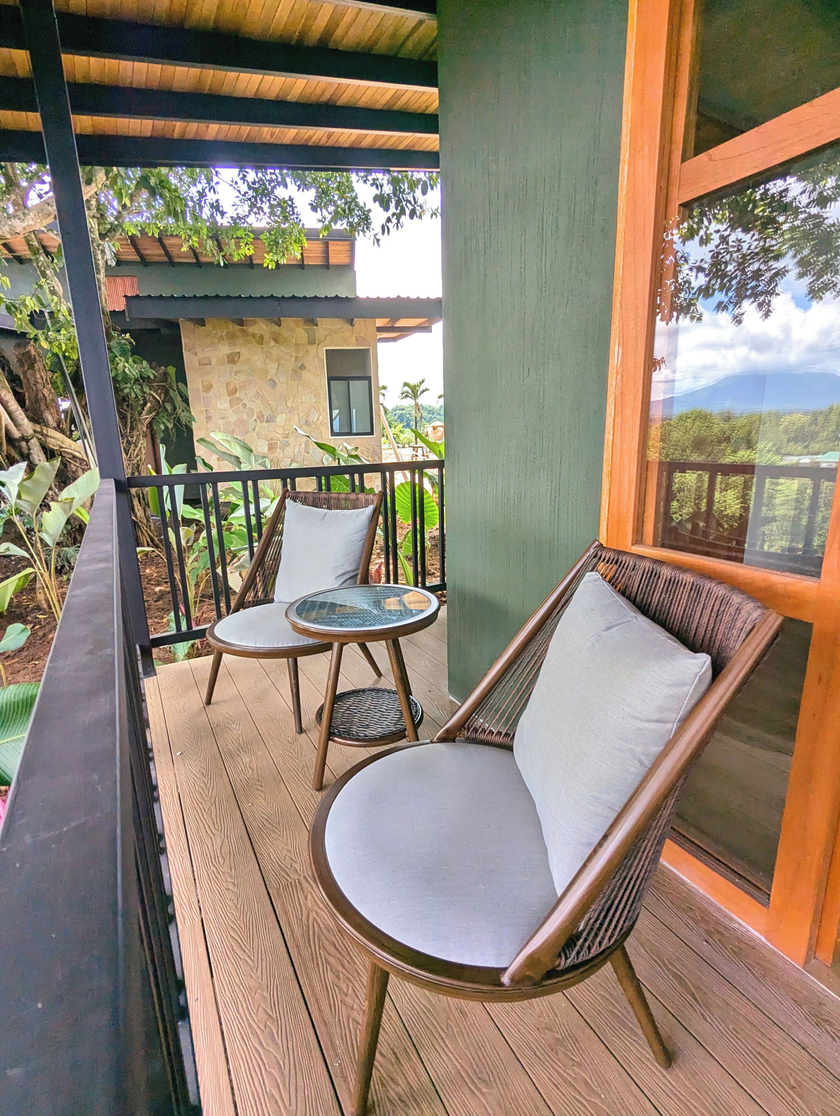 Une terrasse en bois avec deux fauteuils en osier et une petite table.