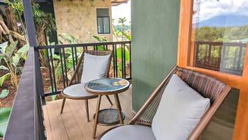 Une terrasse en bois avec deux fauteuils en osier et une petite table.