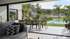 Un salon moderne doté d’une grande fenêtre, d’un canapé, d’une table basse et d’un coin repas avec des chaises et une table.