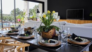 Une table à manger dressée avec des assiettes, des verres et un centre de table composé de fleurs jaunes.