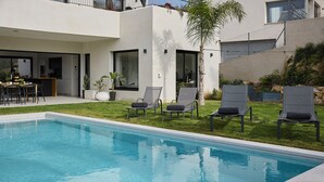 A modern pool area with a clear blue pool, surrounded by a well-maintained lawn and four lounge chairs. - Villa Casa Selva - Luxury and nature only 7 minutes drive from Sitges (Sitges)