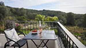 A balcony with a table, a bottle, and glasses, overlooking a forested area. - Villa Casa Selva - Luxury and nature only 7 minutes drive from Sitges (Sitges)