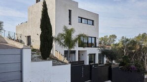 A modern two-story house with a flat roof, a large window, and a tall tree in front. - Villa Casa Selva - Luxury and nature only 7 minutes drive from Sitges (Sitges)