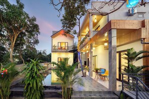 Un hotel moderno de dos pisos, con zona de estar al aire libre y una piscina pequeña.