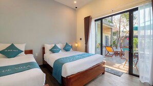 A hotel room with two beds, a balcony with a table and chairs, and a view of the outside. - Ha Blue Villa - Hoi An (Da Nang)
