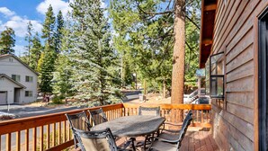 A wooden deck with a table and chairs, surrounded by trees and a house. - Tahoe Retreat with Decks and Separate Studio (Tahoe Vista)