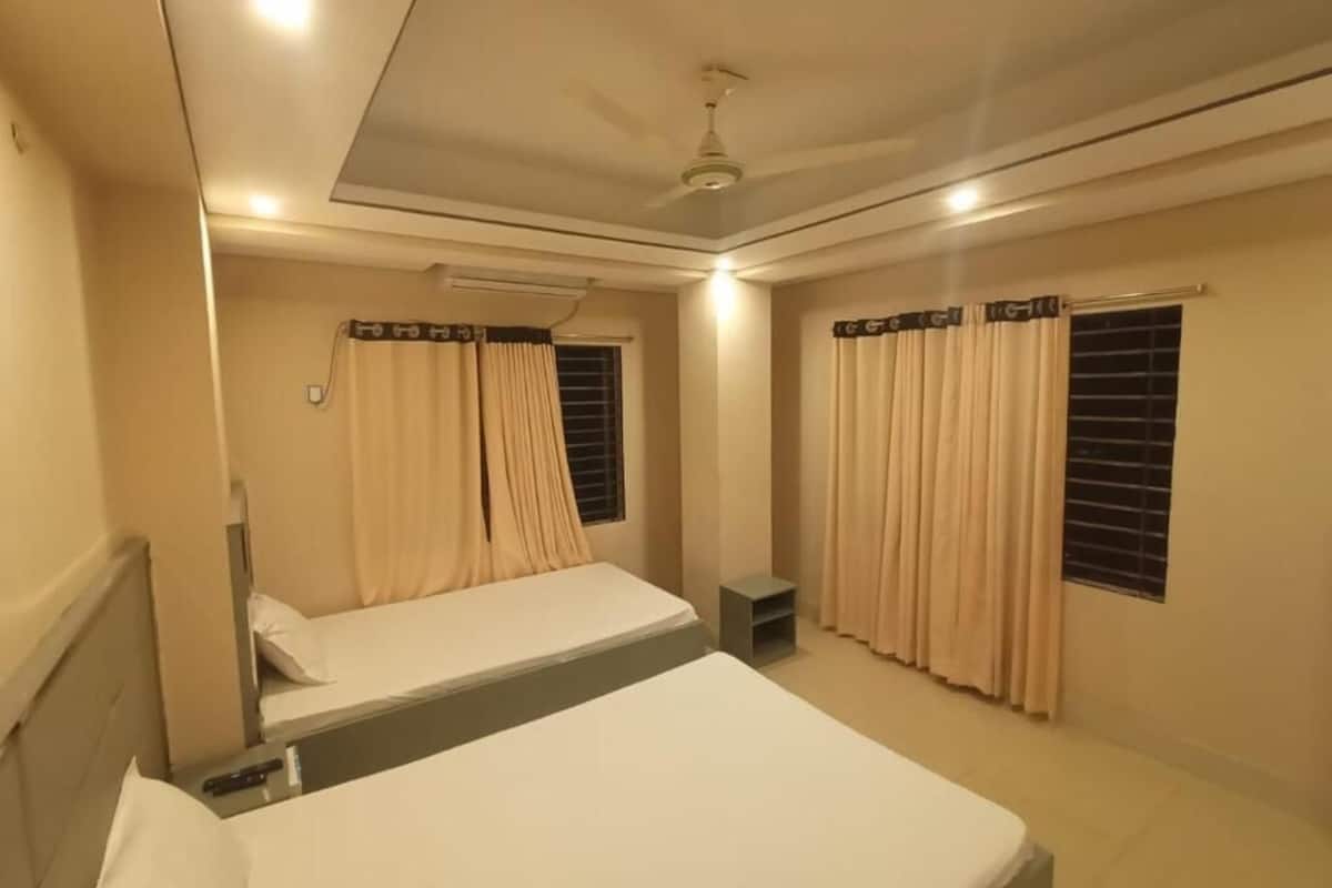 Une chambre d’hôtel avec deux lits simples, un ventilateur de plafond et une petite table.